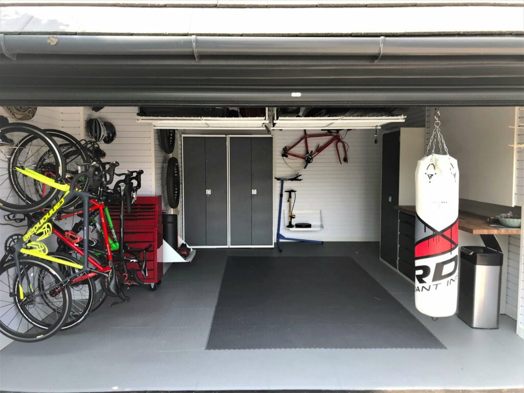 A refurbished garage space with bike racks attached to the wall, a metal cabinet and a punching bag hanging from the ceiling.