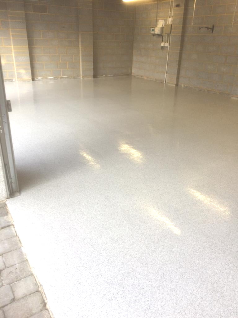 A garage with a shiny resin floor and bare block walls.