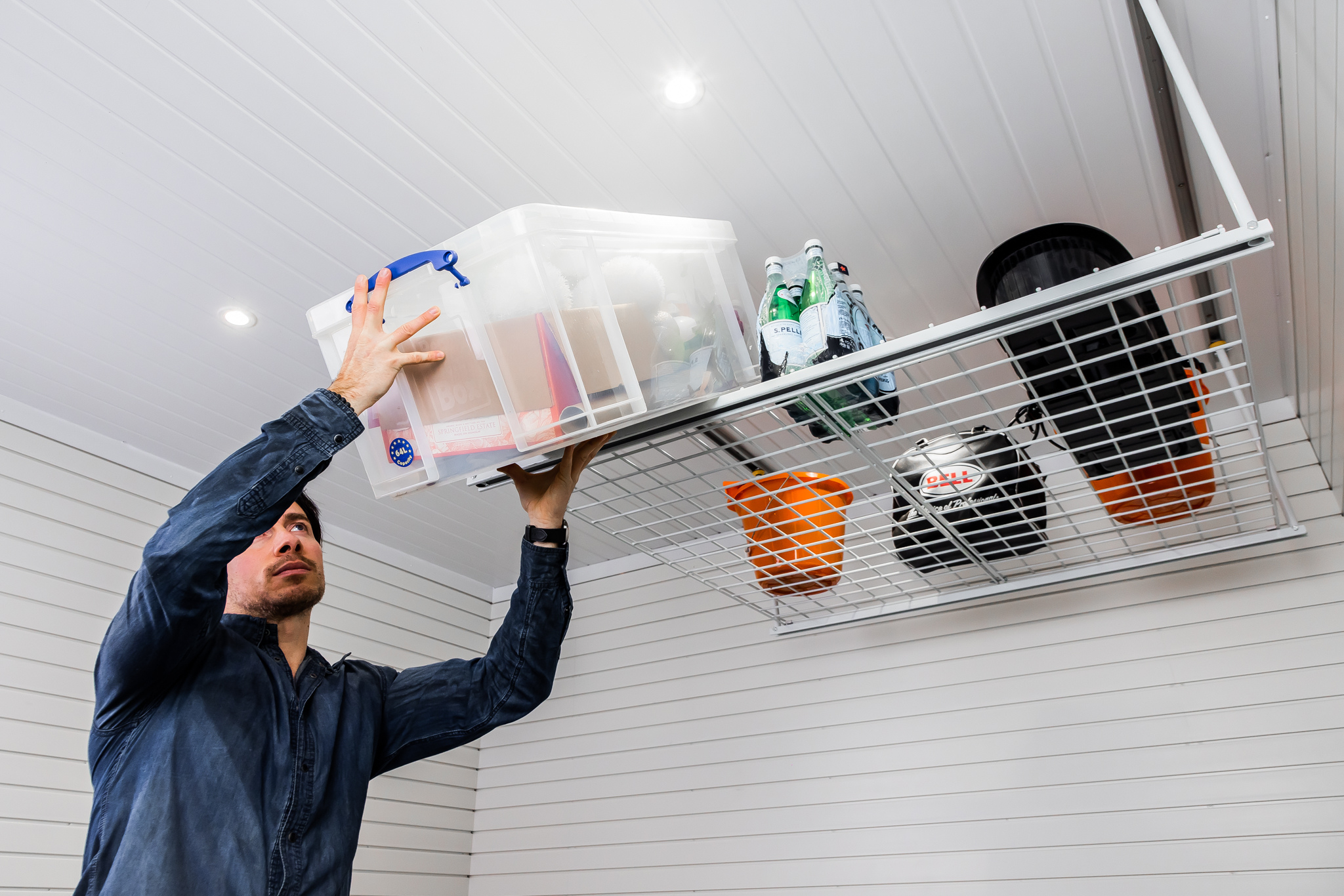 a man placing a box on a garage ceiling storage rack.
